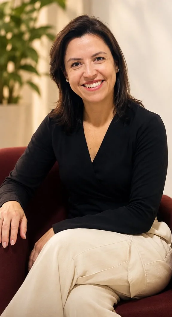 Fernanda Silva, psicóloga, sorrindo sentada numa poltrona bordô